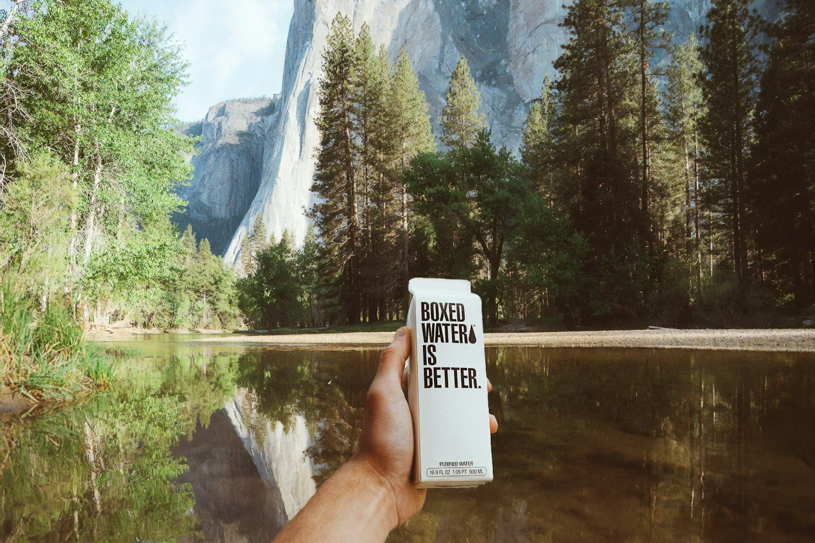 Offener Koffer auf Holzboden mit akkurat gerollter Sommerkleidung, Reisepass, Sonnenhut, Reiseführer und Kamera in warmem Morgenlicht.